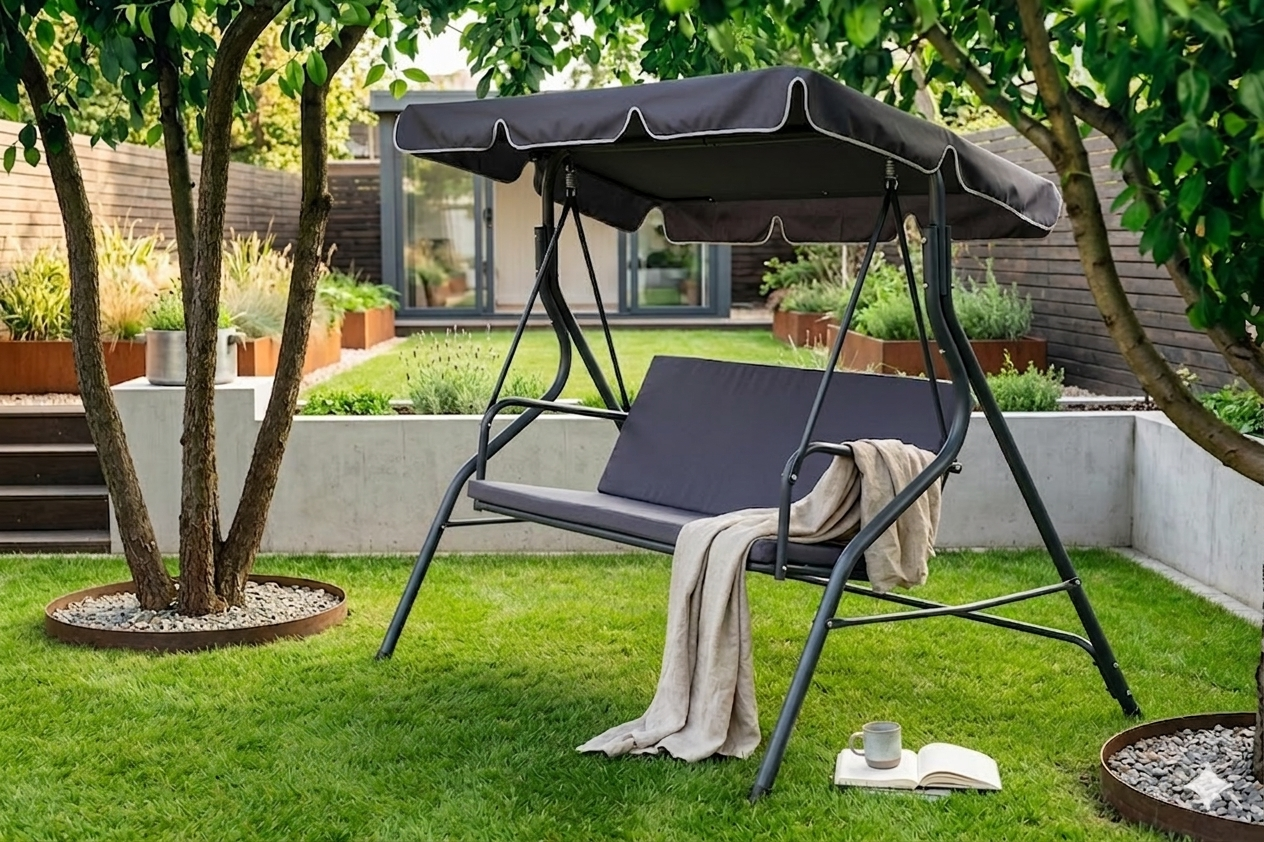 Grafitowa huśtawka ogrodowa z ciemnym daszkiem i siedziskiem w nowoczesnym ogrodzie, gotowa na sezon. Zobacz, jak odświeżyć swoją huśtawkę i dobrać nowe tekstylia do ogrodu.